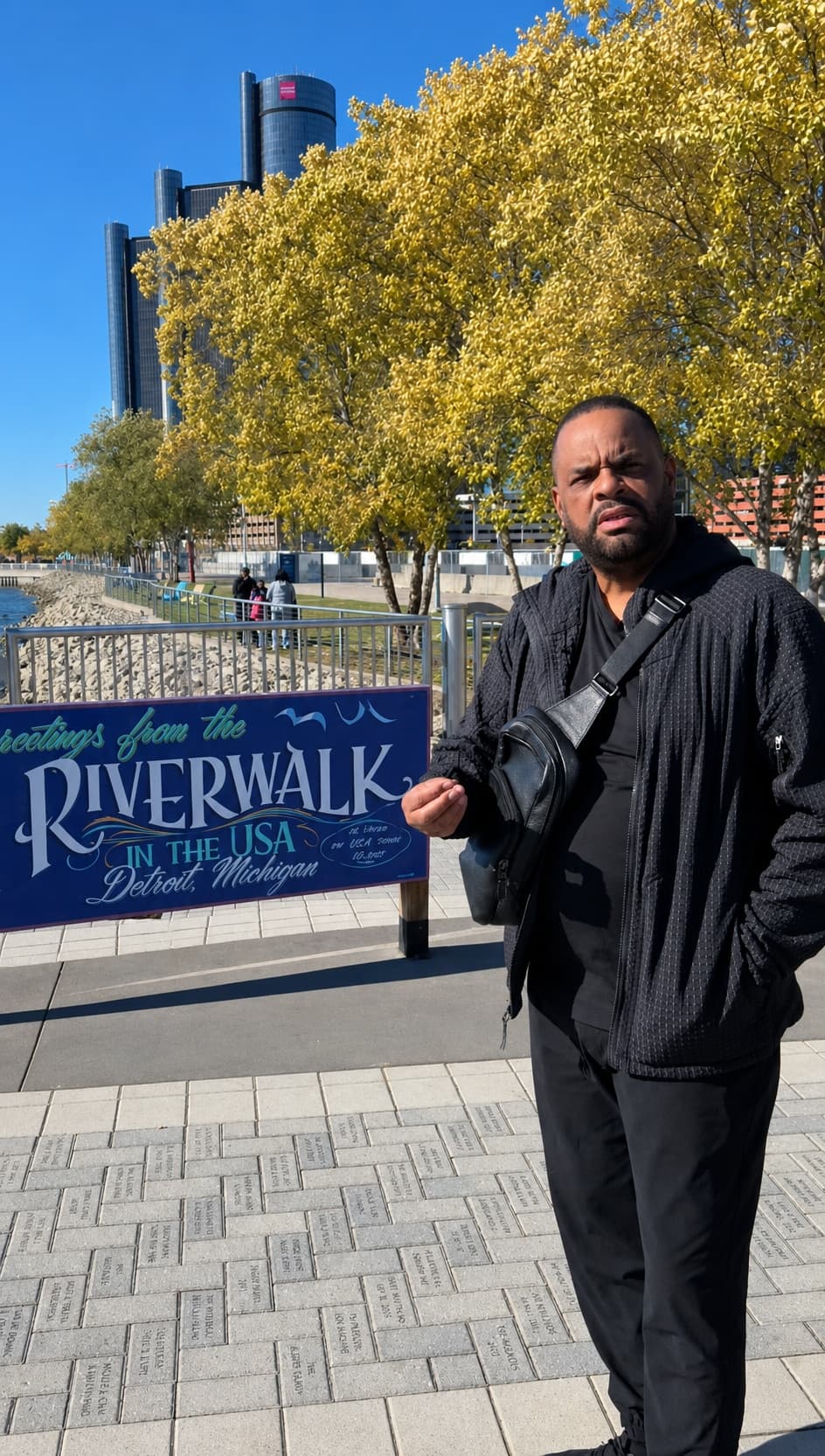 Michael A. Evans on the Detroit Riverwalk, with the Renaissance Center on the riverfront behind him.